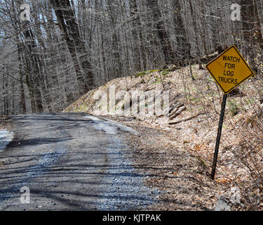Dirt logging road in the Adirondack Mountains wilderness with a warning to watch for log trucks. Stock Photo