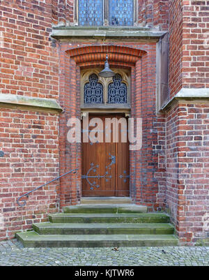Old wooden door in brick wall with iron fittings, steps and ornate windows Stock Photo