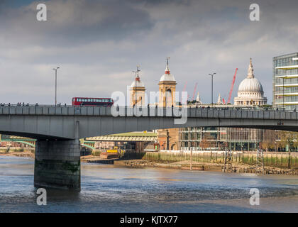 Iconic London red double-decker buses crosses London Bridge with St. Paul's Cathedral in background Stock Photo