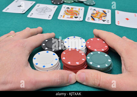 Stack of poker chips in two hands and cards on a gambling table with chips Stock Photo