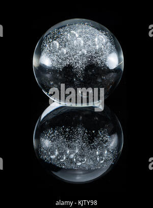 Closeup of a glass sphere standing on a black reflective surface Stock Photo