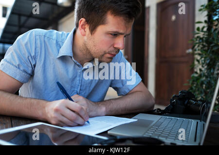 A young man makes a business plan for his personal business. Stock Photo