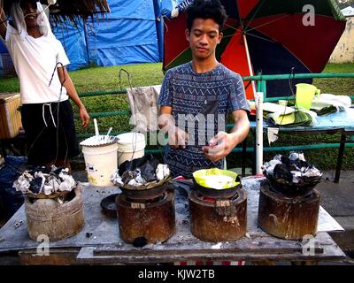 ANTIPOLO CITY, PHILIPPINES - NOVEMBER 25, 2017: A vendor sells a Filipino delicacy called rice cake at a public park. Stock Photo