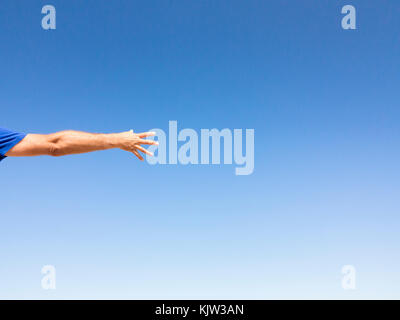 Open hand against blue sky Stock Photo