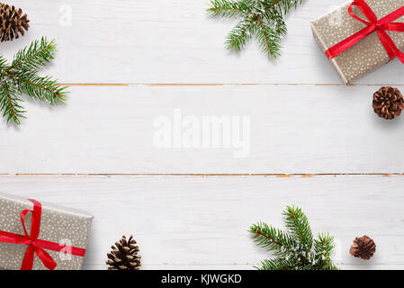 Christmas background with branches of fir, pinecones and gift boxes on white wooden board. Stock Photo