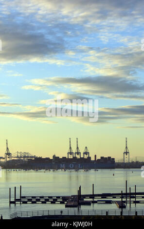 The evening light in autumn and sunset skies over the port of southampton docks on the solent in hampshire uk. International shipping port on solent. Stock Photo