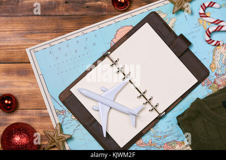 travel , trip vacation, tourism mockup - close up of clothes, christmas decorations and toy airplane and touristic map on wooden table. Empty space yo Stock Photo