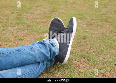 Girl lying on grass, close up of her crossed legs Stock Photo