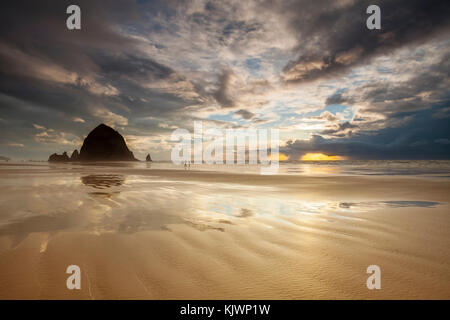 Clearing storm at sunset over Cannon Beach, Oregon. Golden sunlight is seen breaking through the clouds. Stock Photo