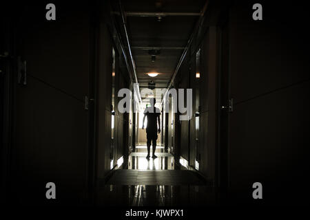 Man walking down a long dark corridor