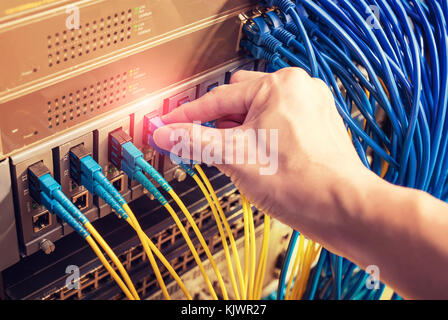 administrator holding network cables connected to servers Stock Photo