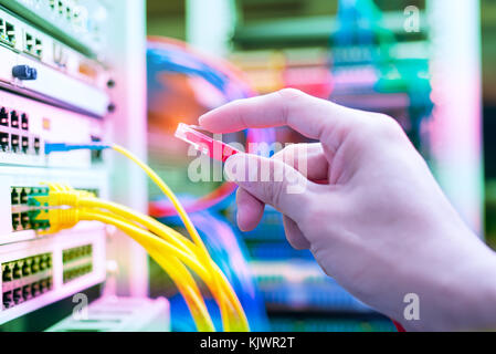 administrator holding network cables connected to servers Stock Photo