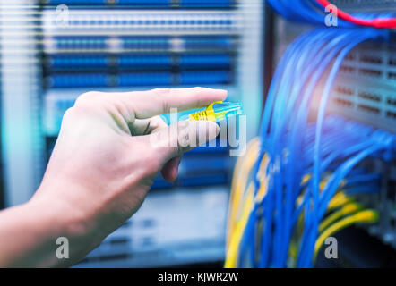 administrator holding network cables connected to servers Stock Photo