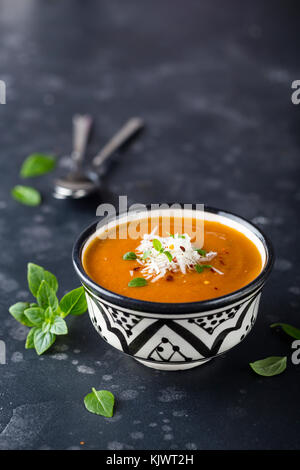 Creamy tomato soup served with parmesan cheese and fresh basil Stock Photo