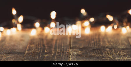 Blurred Christmas lights on wooden rustic table. Moody Christmas background with copy space Stock Photo