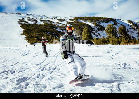 Young man rides snowboard and enjoying a sunny winter day on mountain slopes. Stock Photo