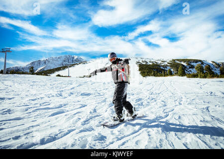 Young man rides snowboard and enjoying a sunny winter day on mountain slopes. Stock Photo