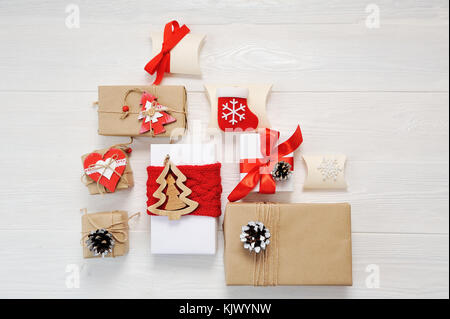 Mockup paper parcels wrapped tied with tags. A red heart and some christmas gift boxes wrapped with paper kraft and tied with red and white bakers twine on a white wooden table. Vintage Style Stock Photo