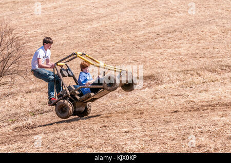 Two teenage boys airborne while  riding a fast go kart in a field in Kentucky USA Stock Photo