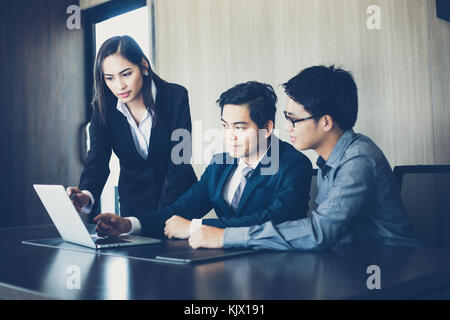 Asian businessmen and group using notebook for business partners discussing documents and ideas at meeting and business women smiling happy for workin Stock Photo