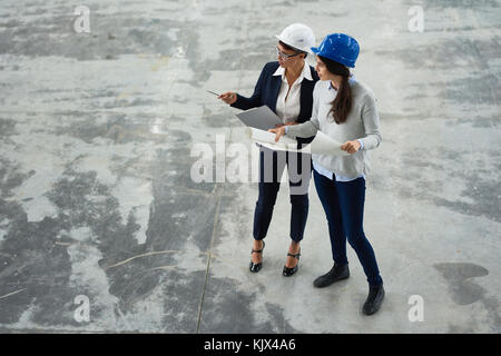 Ambitious confident female architects visiting construction site and discussing building plan viewing place Stock Photo