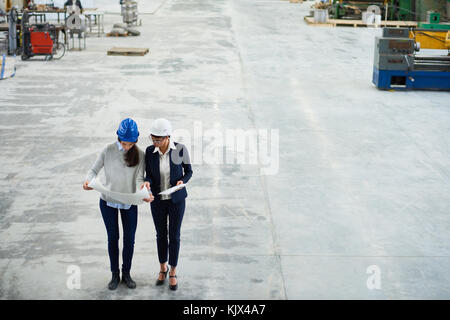 Concentrated female investor working with young architect who showing sketch to boss explaining plan of work Stock Photo
