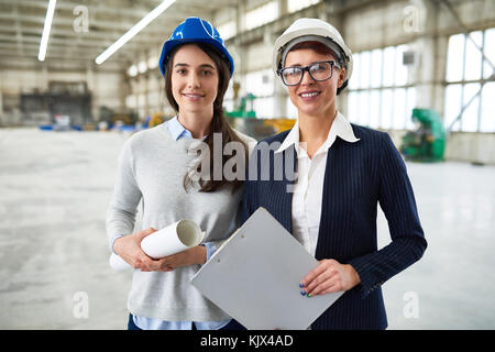 Cheerful beautiful female investor meeting with ambitious young architect at construction site and looking with confidence at camera Stock Photo