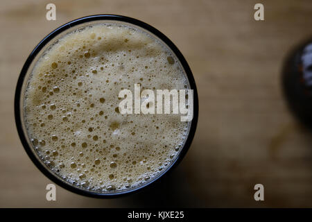 Flat lay view of a pint of beer showing the foamy head of bubbles on the surface Stock Photo