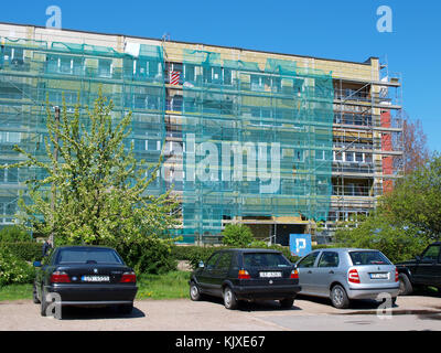 LIEPAJA, LATVIA - MAY 21, 2015: Workers are renewing multistory apartment house near car parking place. Stock Photo