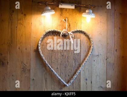 wood heart hanging on wooden wall and light lamp background, Wooden heart shape background. Stock Photo