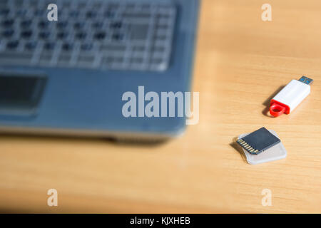 Blurred image. Memory card and USB flash drive on table computer background. Stock Photo