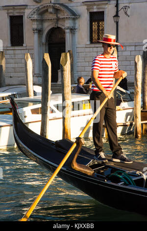 A Gondolier prepares to take unknown tourists on a Gondola trip in Venice on September 12, 2017. Stock Photo