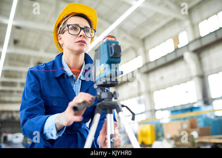 Serious concentrated female engineer focusing on survey line while making measurements at construction site Stock Photo
