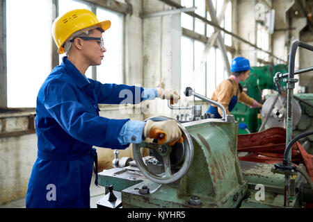Concentrated confident engineer working on tailstock and rolling wheel in factory workshop Stock Photo