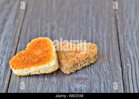 Hearts are cut out from bread. Hearts from rye and white white loaf. Composition on an old wooden table. Close up, selective focus Stock Photo