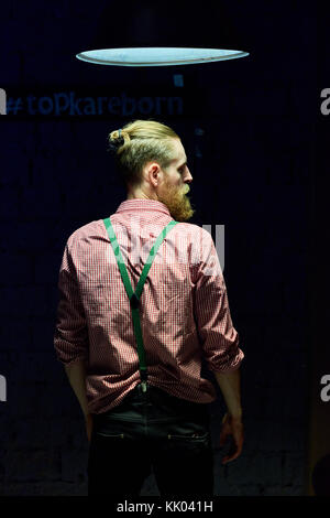 Rear view portrait of handsome bearded man  posing confidently against black background drowning in harsh contrasted spot light from above Stock Photo
