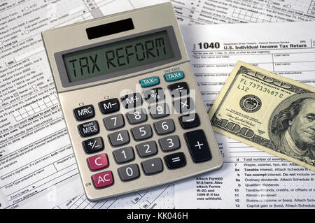 tax reform text on calculator screen with hundred dollar bill on 1040 income tax form Stock Photo