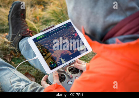 Man navigating a flying drone with remote control.Man in countryside flying drone and taking pictures. Stock Photo