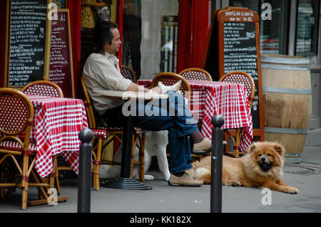 Man and his dogs relaxing at the bistro table in Paris waiting to be served Stock Photo