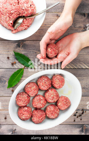 Female hands prepare meatballs on the wooden table, top view Stock Photo