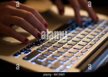 Woman typing on keyboard at night. Stock Photo