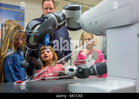 Curious children looking at demonstration with industrial robot arms at exposition about robotics and artificial intelligence / AI Stock Photo