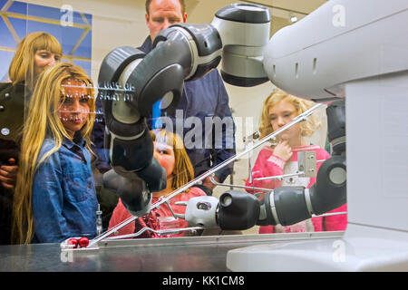 Curious children looking at demonstration with industrial robot arms at exposition about robotics and artificial intelligence / AI Stock Photo