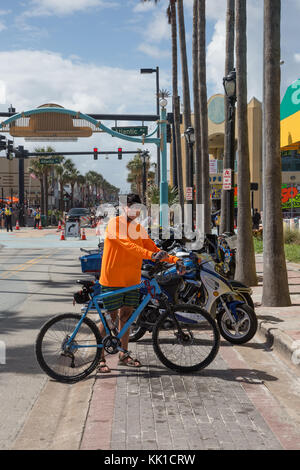 Bicyclist wearing orange shirt lined up with parked motorcycles at Biketoberfest in Daytona Beach, Florida Stock Photo