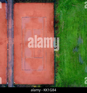 Tennis court with red gravel next to a lawn, abstract effect by vertical aerial photograph with drone Stock Photo