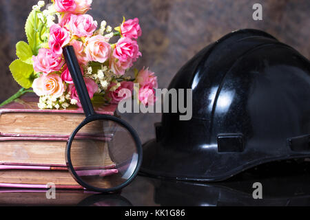 Group of objects on a granite, magnifying glass, old books,artificial flower, black helm ,Still life Stock Photo