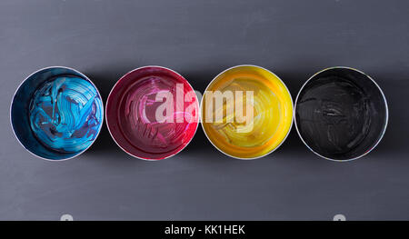 Top view of old CMYK paint cans on dark background. Colorful background. Stock Photo
