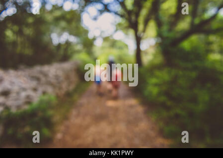 Family hiking on country road with rock fence and woods. Mother and daughters are trekking through rough terrain on island Silba Croatia. Intentionall Stock Photo