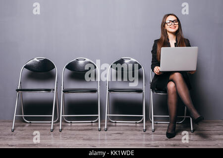 young smiling office worker woman sitting on wood floor chair using mobile laptop computer prepare interview meeting file Stock Photo