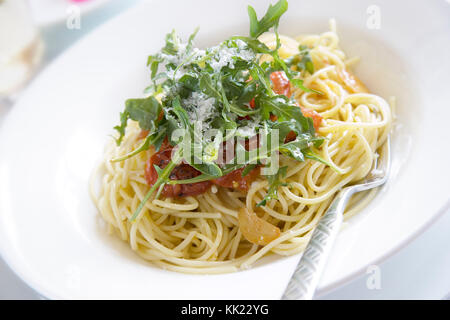 Spaghetti with sun dried tomatoes, rocket, Parmesan cheese and Parmesan crisps Stock Photo